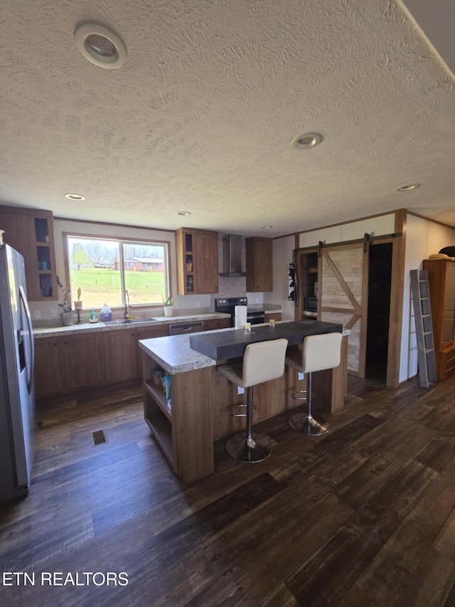 kitchen featuring open shelves, a barn door, dark wood finished floors, stainless steel appliances, and a kitchen island