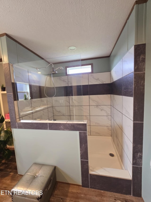 bathroom with a textured ceiling, wood finished floors, and walk in shower