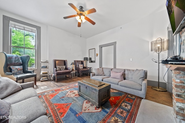 living area with a ceiling fan and wood finished floors