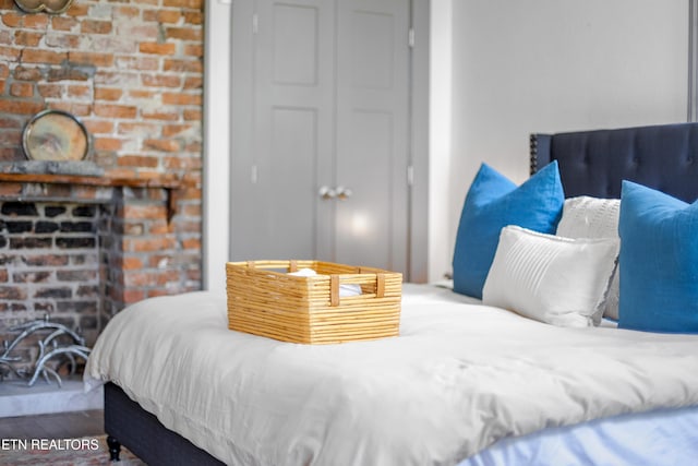 bedroom featuring a closet, wood finished floors, and a brick fireplace