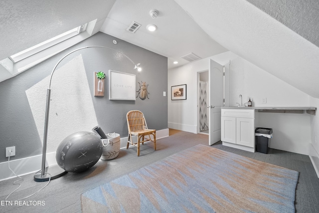 living area featuring baseboards, carpet, vaulted ceiling with skylight, and visible vents