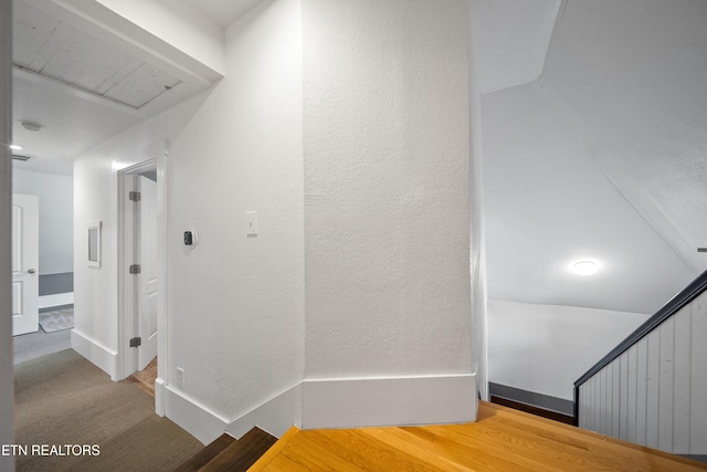 corridor featuring baseboards, an upstairs landing, and a textured wall