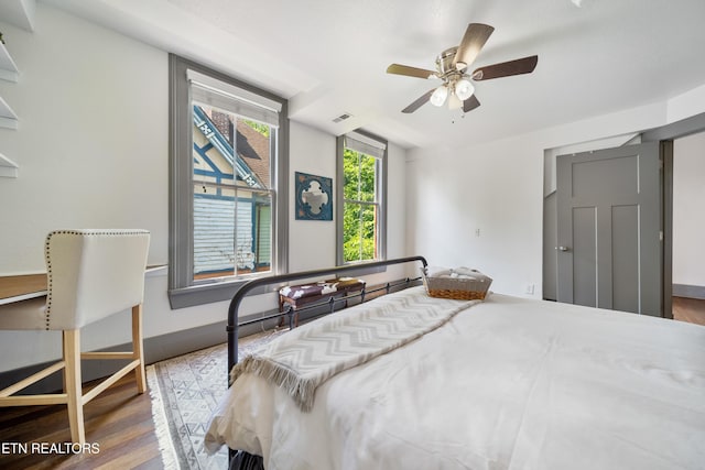 bedroom featuring baseboards, visible vents, wood finished floors, and ceiling fan
