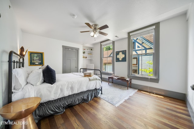 bedroom featuring a ceiling fan, visible vents, baseboards, and wood finished floors