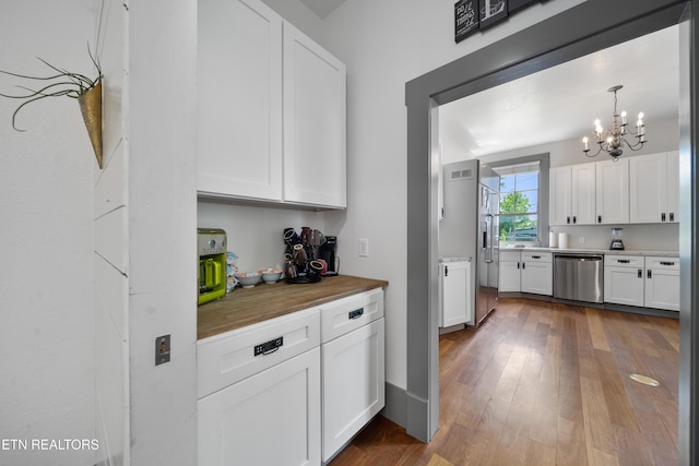 kitchen with an inviting chandelier, white cabinetry, and appliances with stainless steel finishes