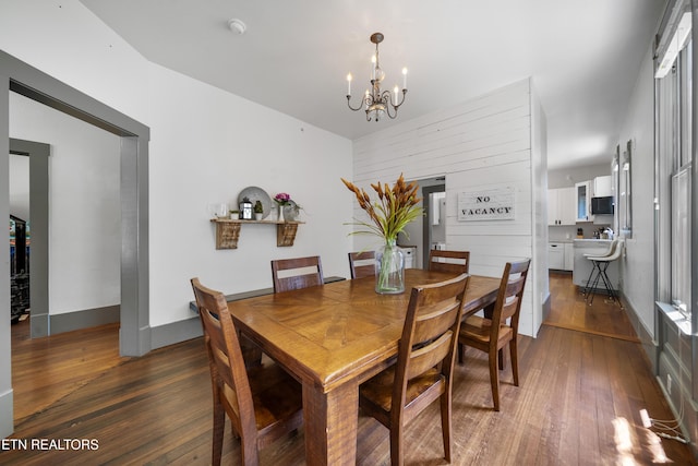 dining space featuring a notable chandelier, dark wood-type flooring, and baseboards