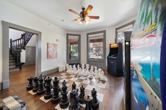misc room with stairs, ceiling fan, baseboards, and hardwood / wood-style floors