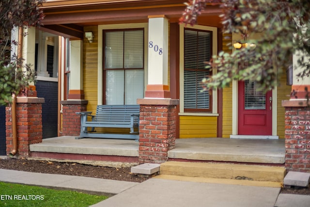 property entrance featuring brick siding and a porch