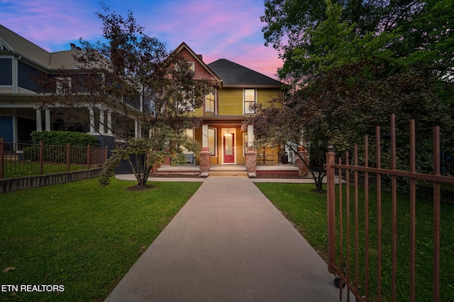 view of front of house with a porch, a front yard, and fence