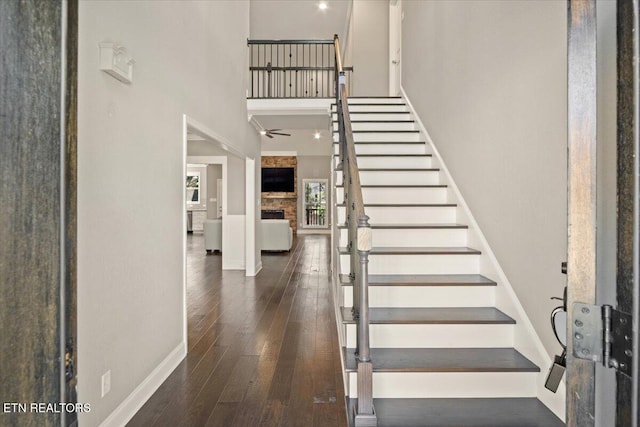 interior space with hardwood / wood-style floors, a towering ceiling, baseboards, and ceiling fan