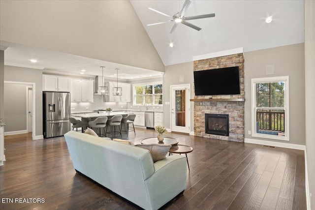living room featuring dark wood-type flooring, baseboards, a fireplace, and ceiling fan