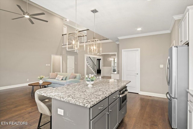 kitchen featuring gray cabinets, dark wood finished floors, open floor plan, stainless steel appliances, and ornamental molding