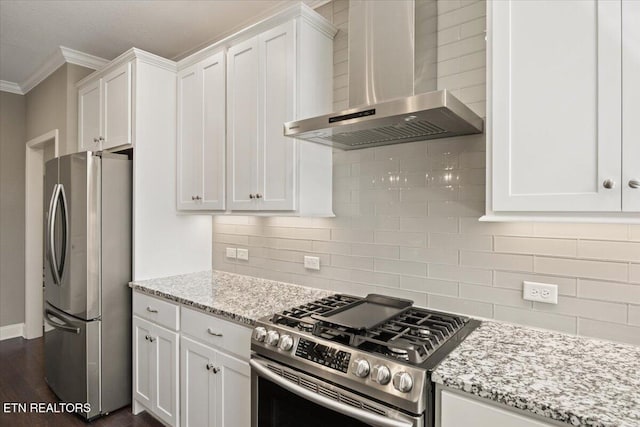 kitchen with white cabinetry, wall chimney exhaust hood, ornamental molding, and appliances with stainless steel finishes