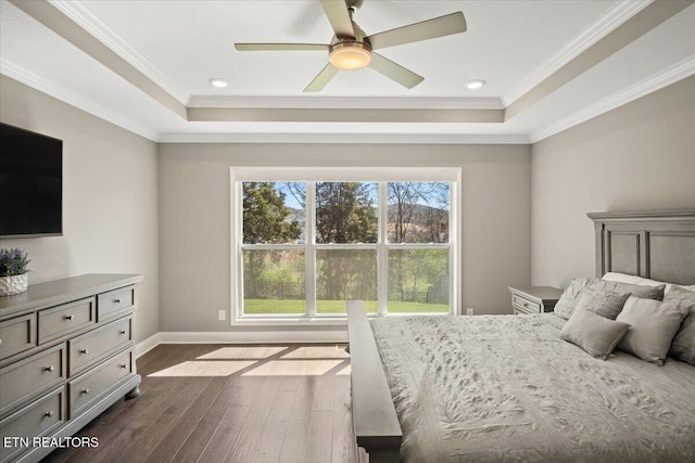 bedroom with a raised ceiling, dark wood-type flooring, baseboards, and crown molding