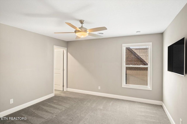 carpeted spare room with baseboards and a ceiling fan