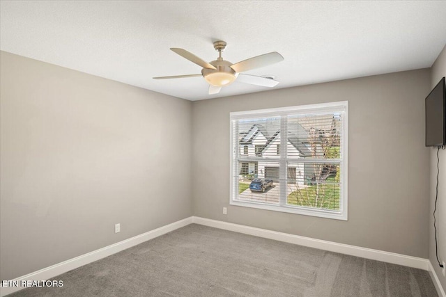 carpeted empty room featuring baseboards and a ceiling fan