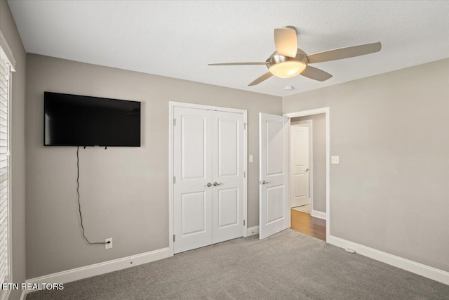 unfurnished bedroom with baseboards, carpet floors, a closet, and a ceiling fan
