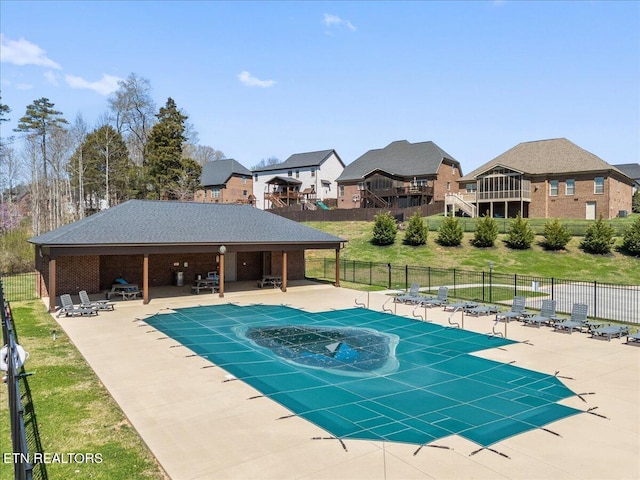 pool with a patio, fence, and a residential view