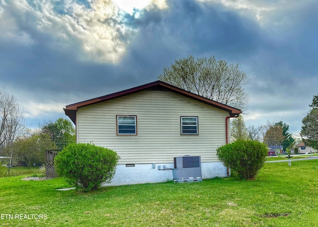 view of side of property featuring crawl space, central AC unit, and a lawn