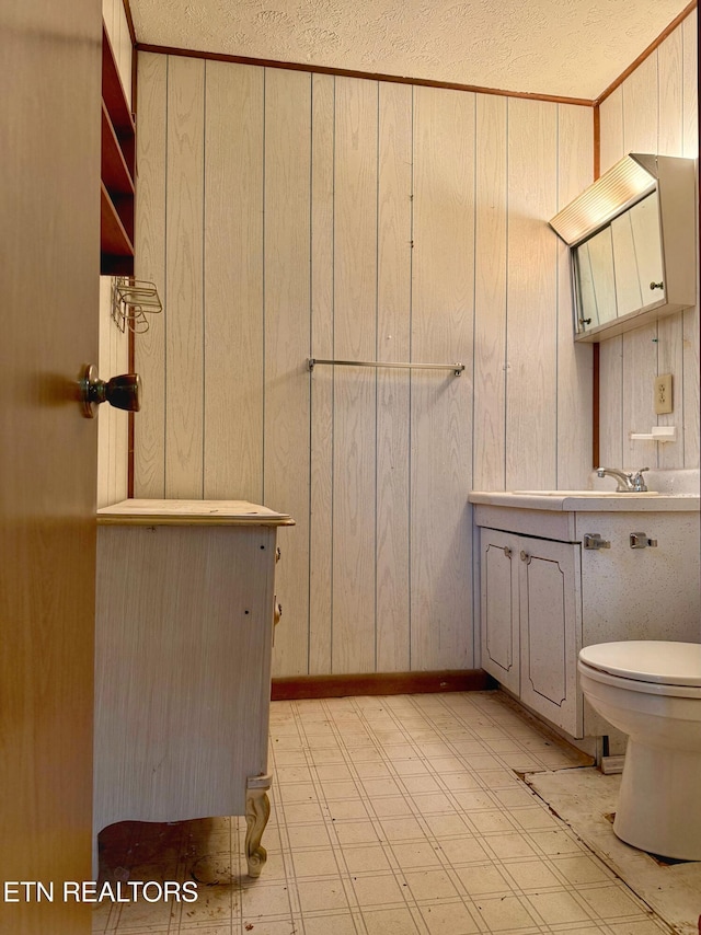 bathroom featuring wood walls, tile patterned floors, toilet, and vanity