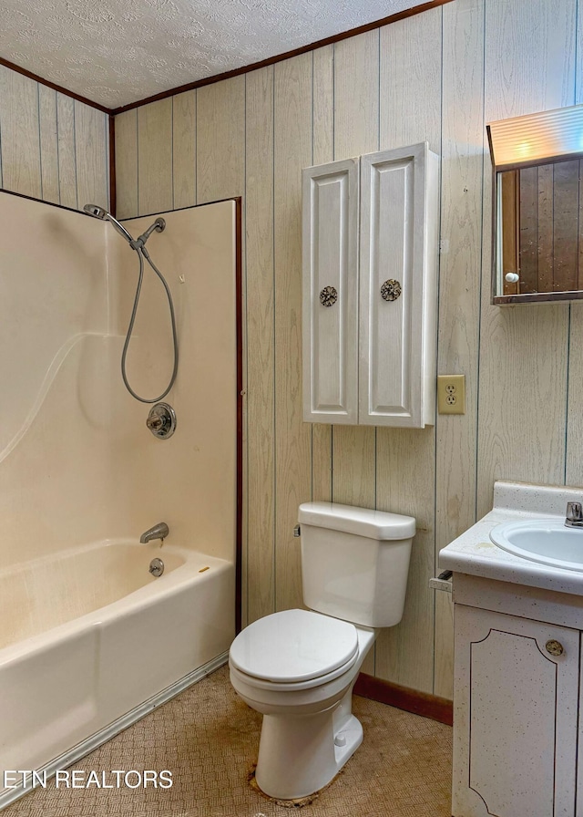 full bathroom with a textured ceiling, wooden walls, toilet, vanity, and shower / tub combination