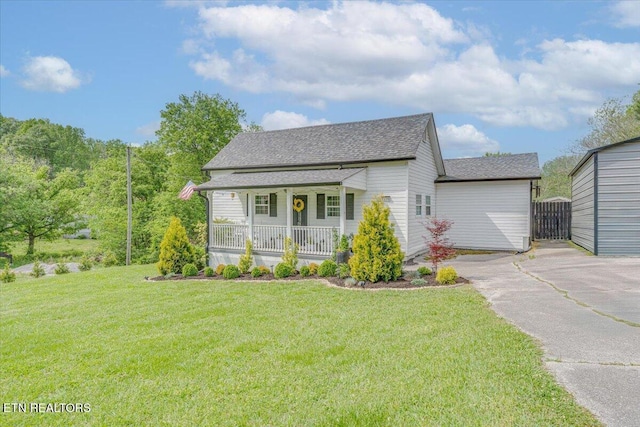 view of front of home with a front yard, driveway, a shingled roof, and covered porch