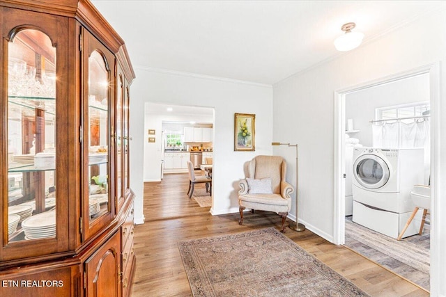 living area with baseboards, washer and dryer, ornamental molding, and light wood finished floors