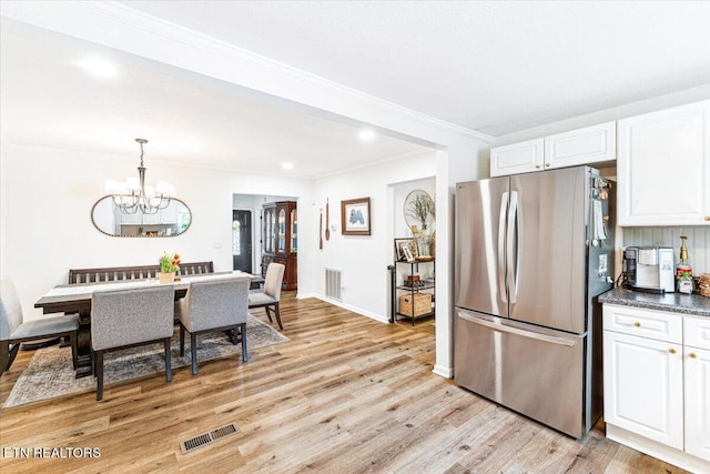 kitchen featuring an inviting chandelier, freestanding refrigerator, light wood-style floors, white cabinetry, and visible vents