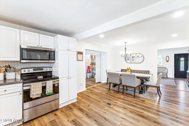 kitchen featuring visible vents, white cabinetry, stainless steel appliances, and light wood-style flooring