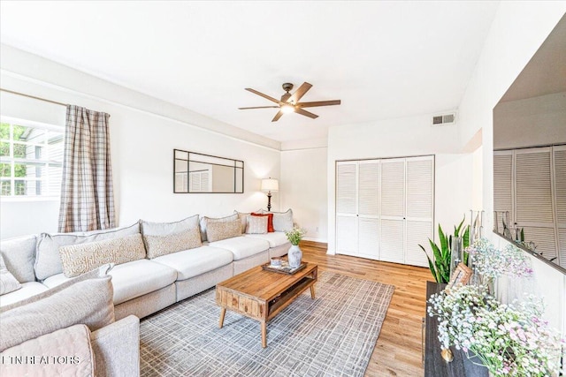 living area featuring visible vents, a ceiling fan, light wood finished floors, and baseboards