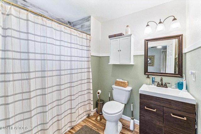 bathroom with curtained shower, baseboards, toilet, wood finished floors, and vanity