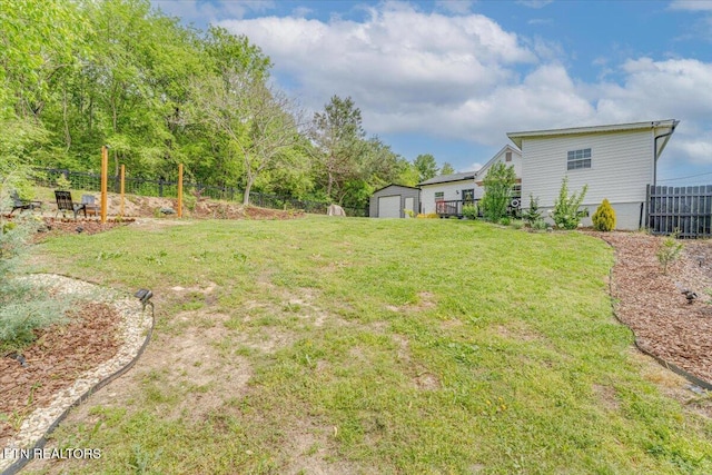 view of yard with an outdoor structure, a detached garage, a storage unit, and fence