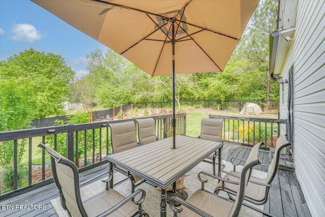 wooden deck featuring a lawn, outdoor dining area, and a fenced backyard
