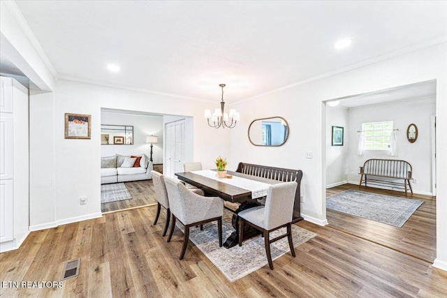dining space with an inviting chandelier, crown molding, and light wood-style flooring