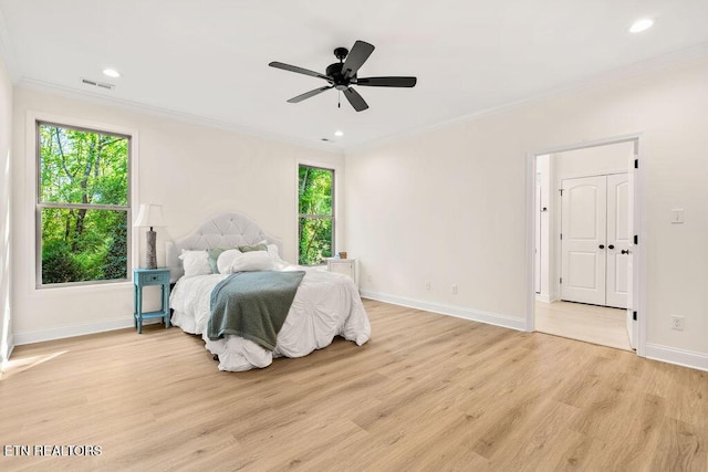 bedroom featuring visible vents, light wood-type flooring, multiple windows, and crown molding