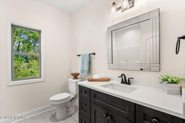 bathroom with baseboards, toilet, and vanity