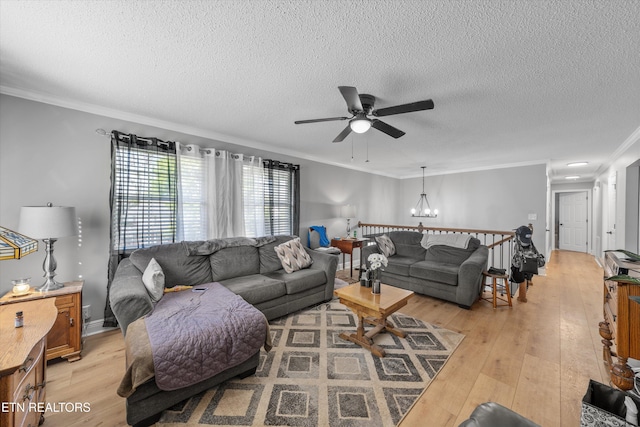 living room featuring ornamental molding, light wood-style flooring, a textured ceiling, and ceiling fan with notable chandelier