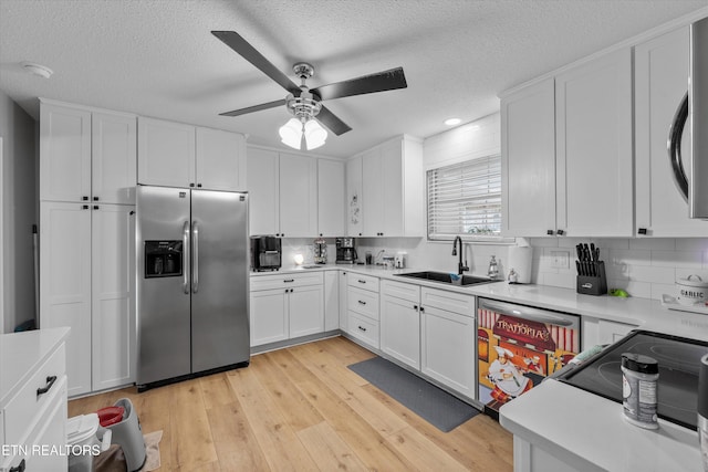 kitchen with stainless steel appliances, light countertops, a ceiling fan, a sink, and light wood-type flooring