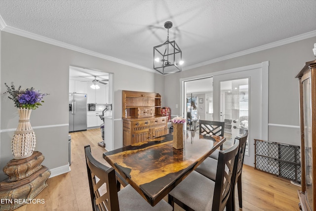 dining space with light wood-type flooring, a textured ceiling, ornamental molding, and ceiling fan with notable chandelier