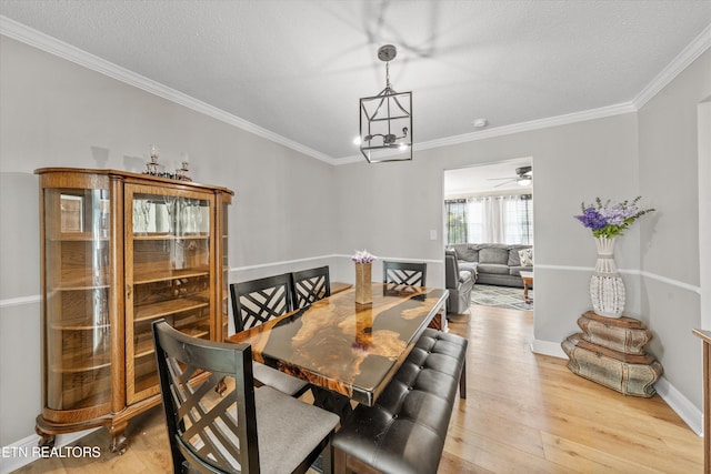 dining room featuring light wood-style flooring, a textured ceiling, ornamental molding, and a ceiling fan