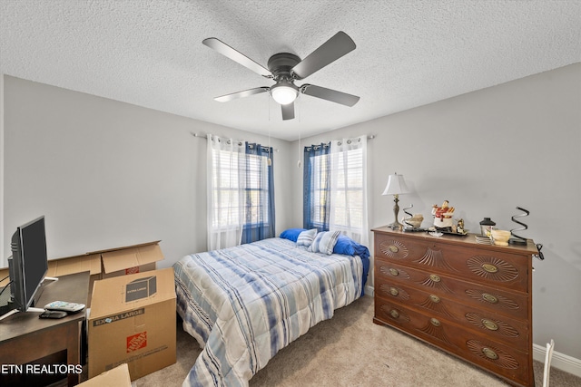 carpeted bedroom with a textured ceiling, baseboards, and ceiling fan