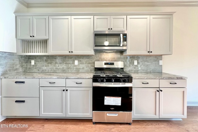 kitchen with light wood-style flooring, stainless steel appliances, tasteful backsplash, and light stone counters