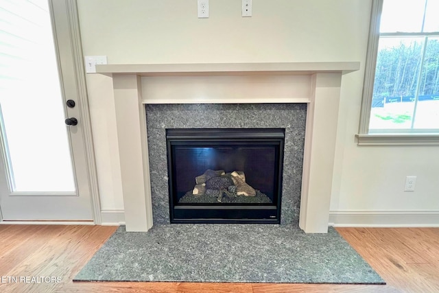 details with baseboards, wood finished floors, and a glass covered fireplace