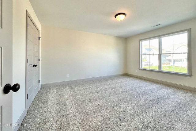 carpeted empty room featuring baseboards and visible vents