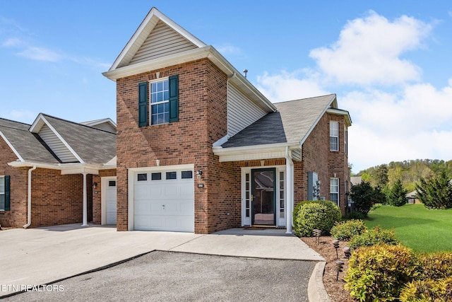 traditional home with roof with shingles, driveway, an attached garage, a front lawn, and brick siding