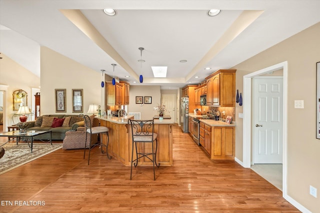 106 Mariners Dr, Fairfield Glade, TN 38558 - kitchen featuring a breakfast bar area, appliances with stainless steel finishes, a raised ceiling, a peninsula, and light wood-style floors