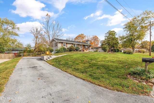 single story home featuring a chimney, driveway, a front yard, and fence