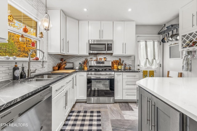 kitchen featuring tasteful backsplash, recessed lighting, white cabinets, appliances with stainless steel finishes, and a sink