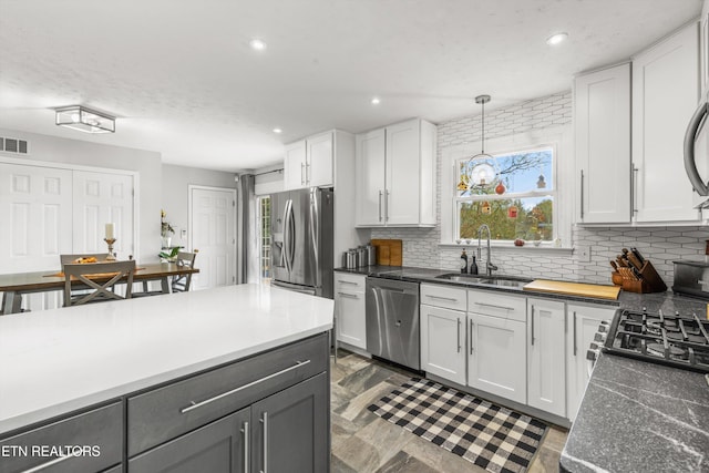 kitchen with a sink, decorative backsplash, white cabinetry, and stainless steel appliances