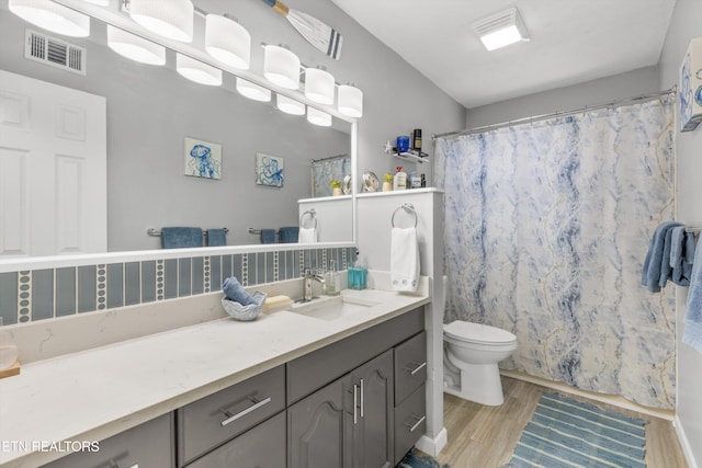 bathroom with visible vents, a shower with curtain, toilet, vanity, and wood finished floors